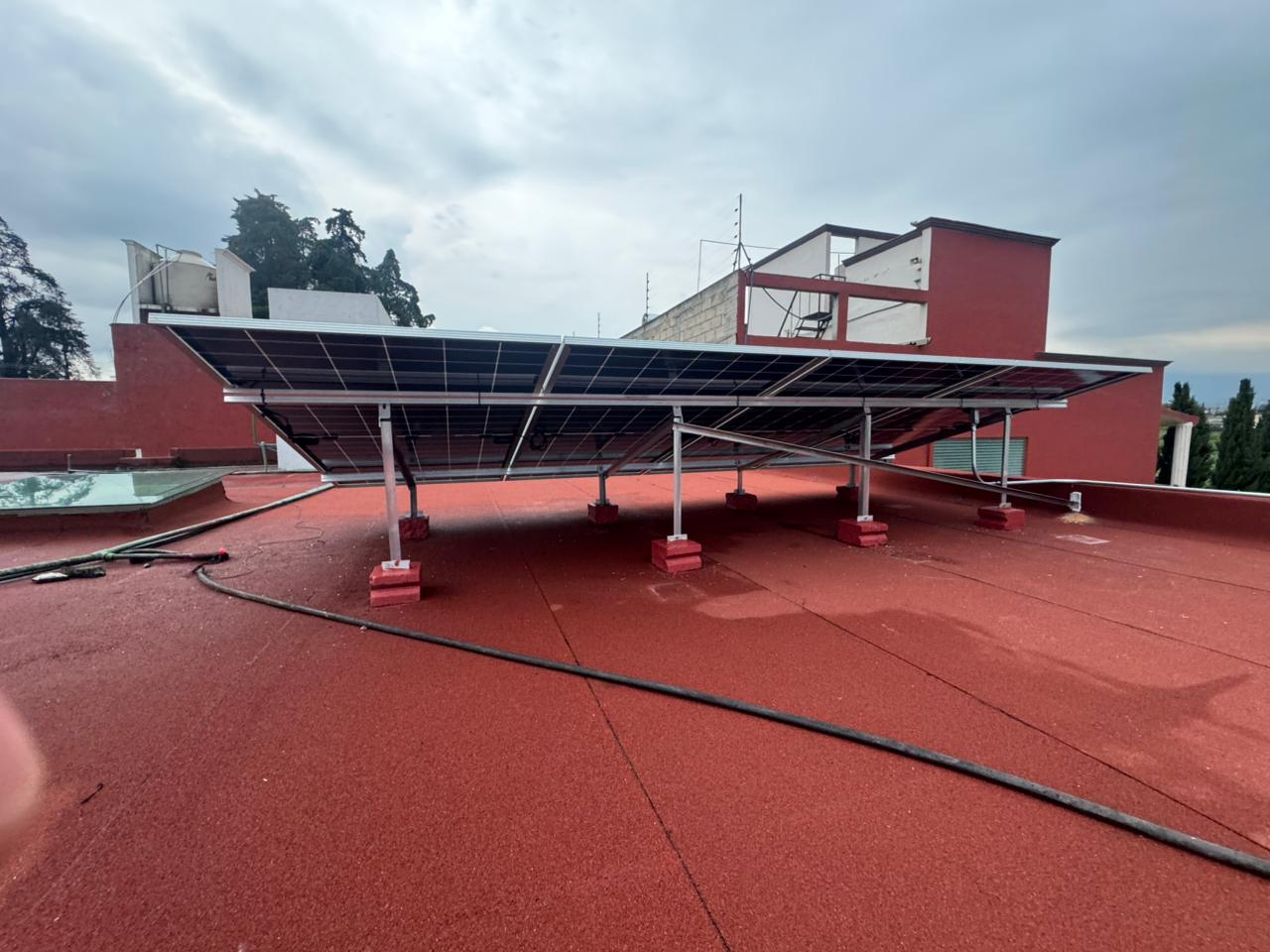 Paneles solares sobre una estructura elevada en una azotea plana, en un día nublado